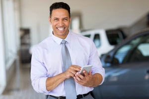 handsome middle aged man using smart phone at car dealership